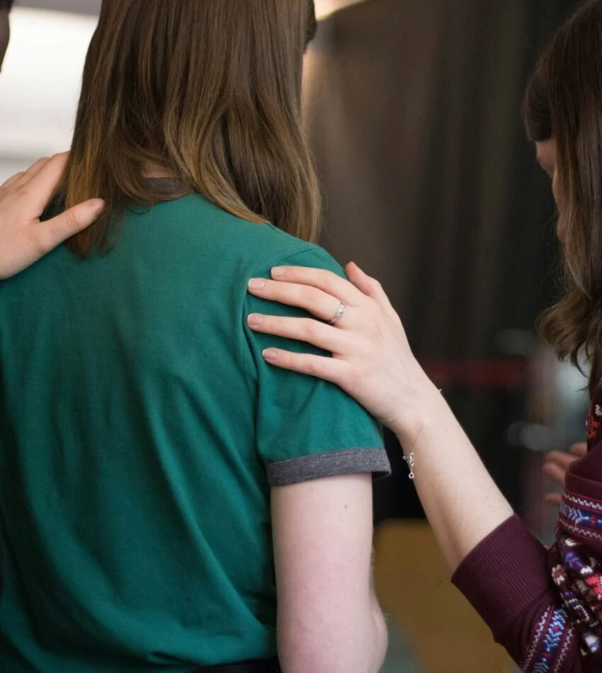 Church friends with their arms around each other in prayer