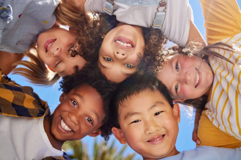 Smiling kids leaning in together in a circle