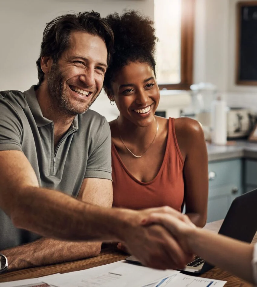 Smiling friends shaking hands across a table